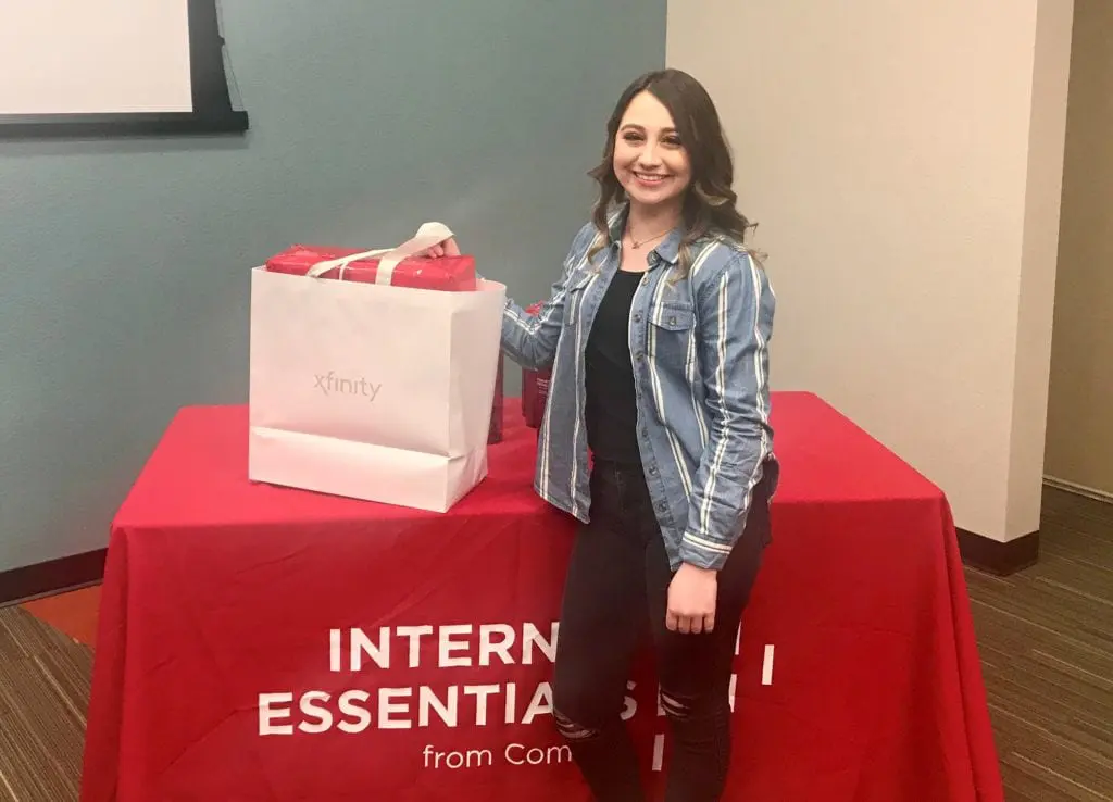 Kimberly Mitchell stands next to her new laptop computer provided by Internet Essentials.