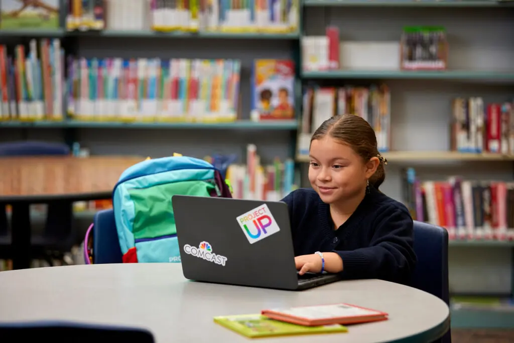 Student working on a laptop with Comcast and Project UP branding.