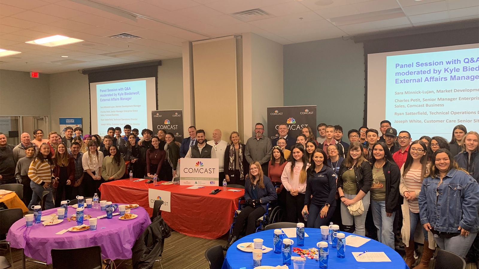 Comcast employees and local students standing in front of Powerpoint screens