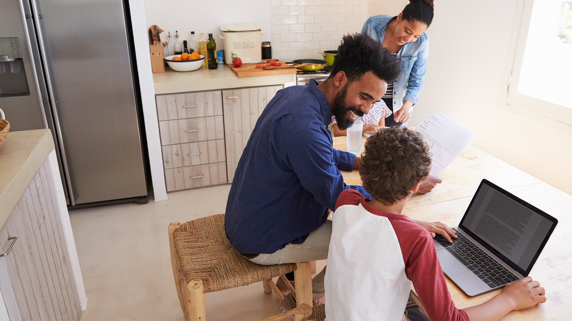 A woman, man and two children sitting at a table looking at a computer.