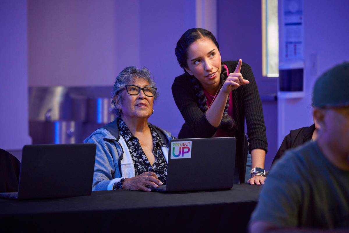 Digital navigator helping a woman learn how to use a laptop.